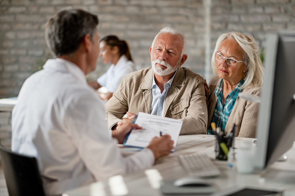 senior couple consulting with healthcare worker about their insurance policy while having meeting clinic