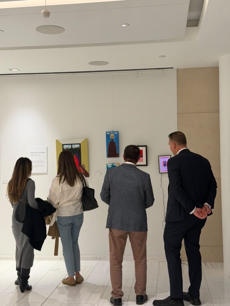 Visitors looking at framed artworks on a gallery wall at the Unpromised Flowers exhibition in New York